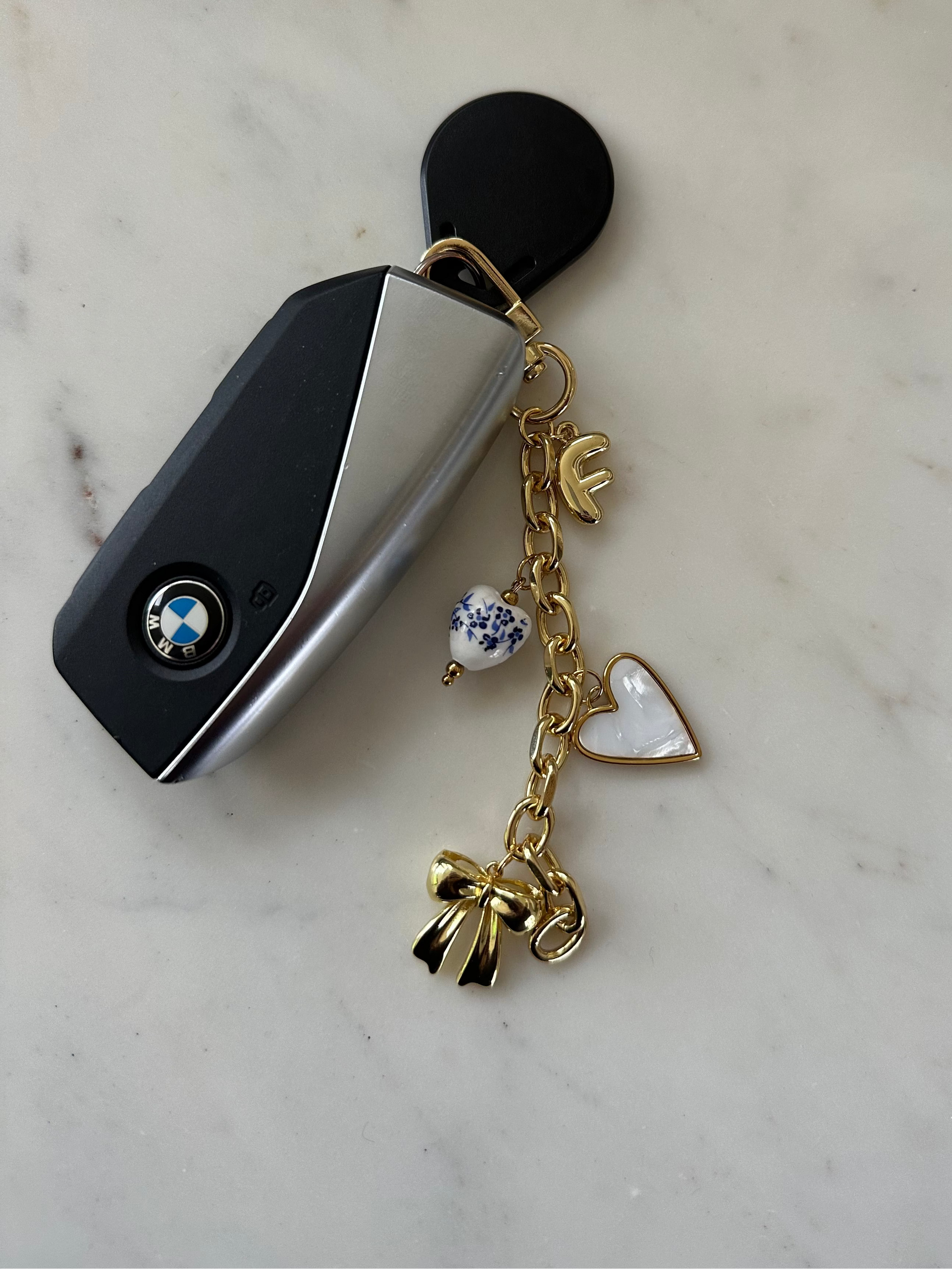gold bag chain with initial charm, heart and bow on key chain.