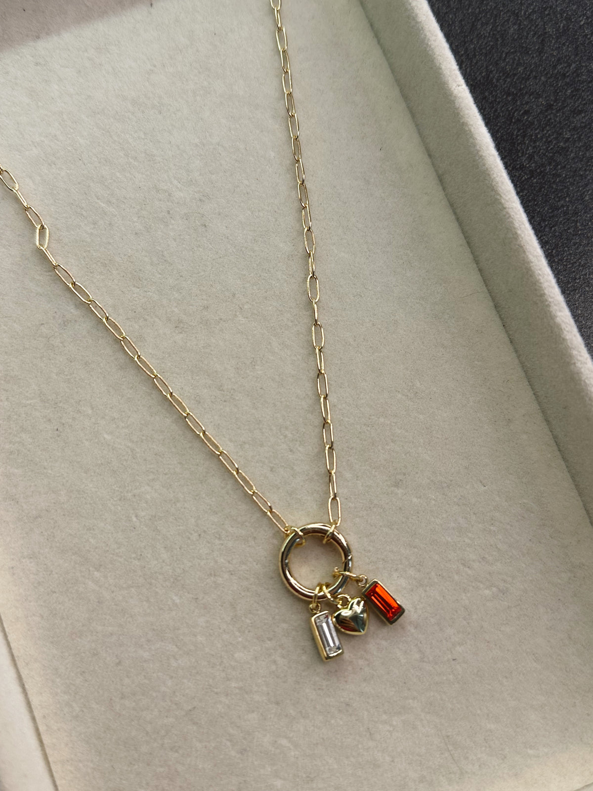 Gold necklace with three charms on a light gray background