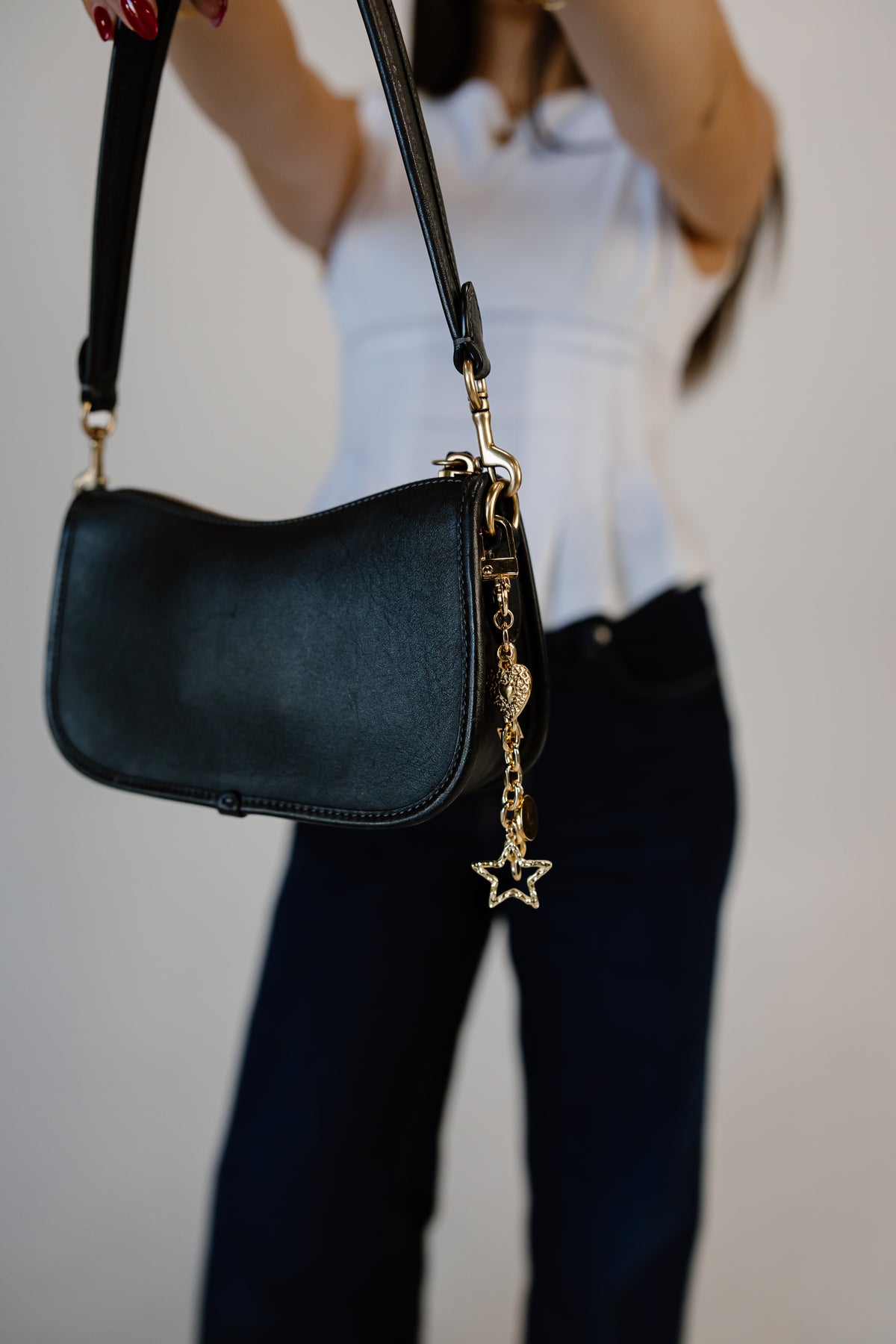 gold bag chain with heart and star charms on black purse.